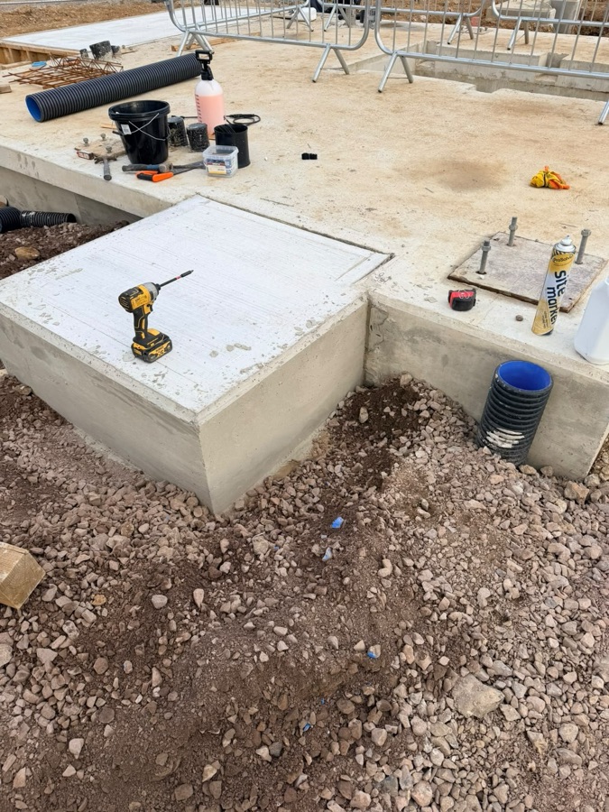 Site photo of a concrete landing pad with a drill, buckets and spray cans on it